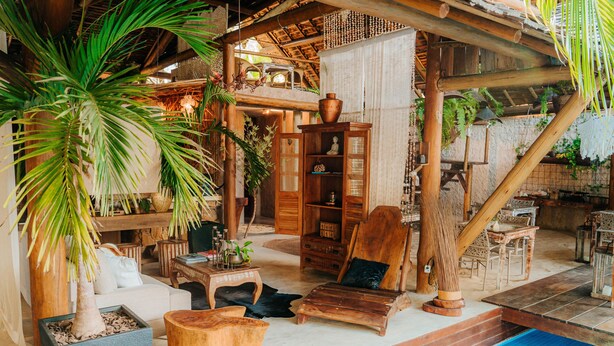 A cozy indoor setting with a wooden lounge area, a pool, and various plants. - Aloha Village Hotel (Amontada)