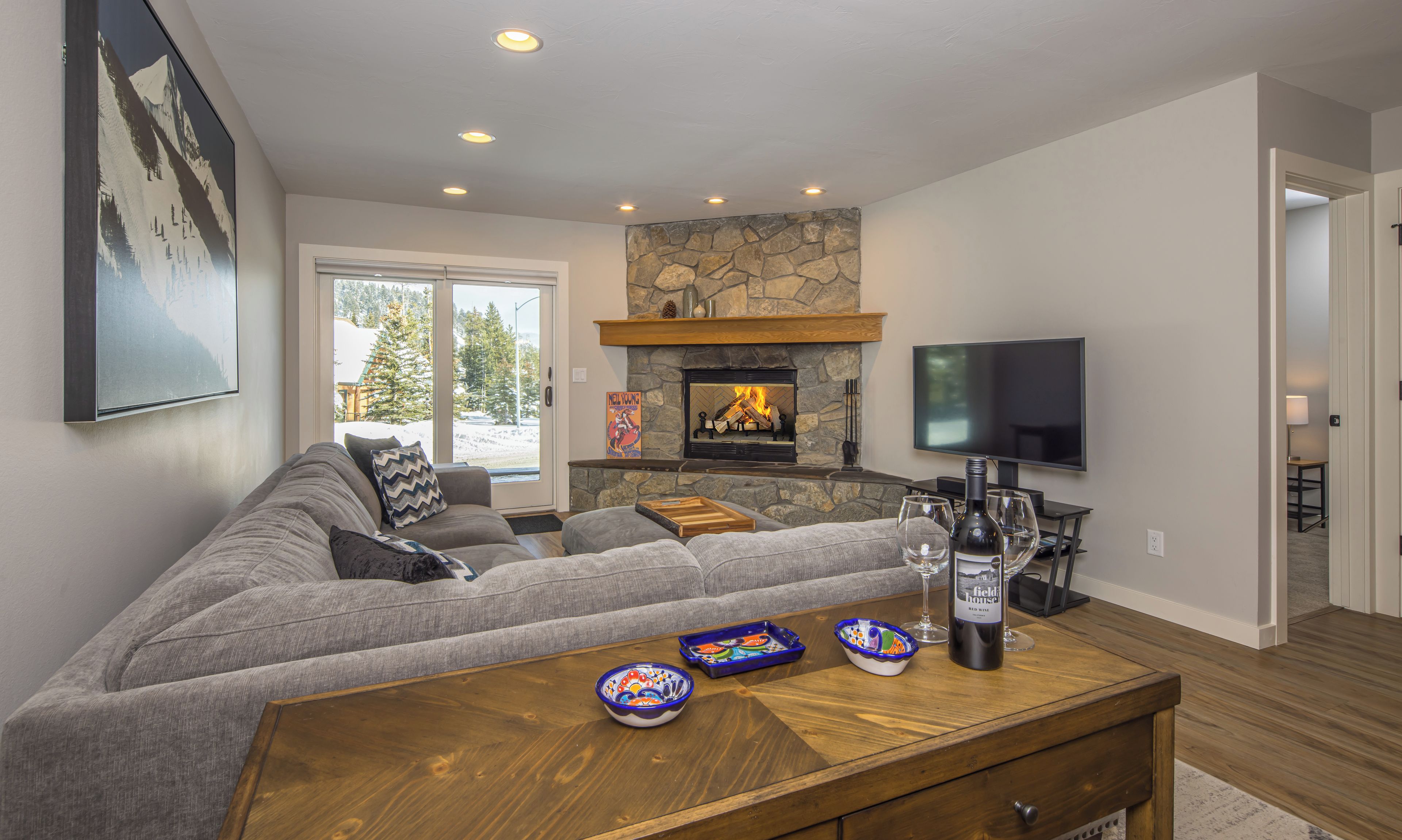 A modern living room with a stone fireplace, a large flat-screen TV, and a cozy seating area.