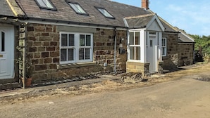 A stone house with a sloped roof, multiple windows, and a chimney. - 2 bedroom accommodation in Longhorsley, Near Morpeth (Longhorsley, Near Morpeth)