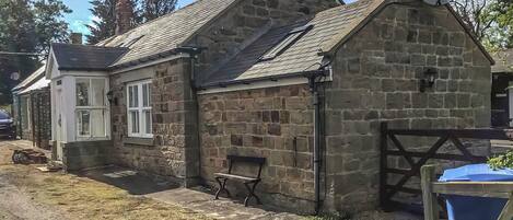A stone building with a sloped roof, a chimney, and a satellite dish.