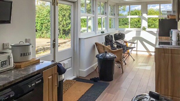 A bright kitchen with large windows, a dining area with chairs, and a view of greenery outside. - 2 bedroom accommodation in Longhorsley, Near Morpeth (Longhorsley, Near Morpeth)