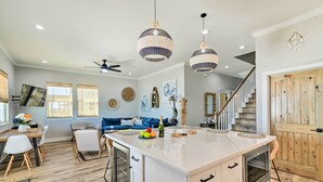 Una cocina amplia con una isla grande, luces colgantes y una escalera de madera.