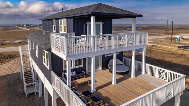 Una casa de dos pisos con balcón, terraza y vista a la playa.