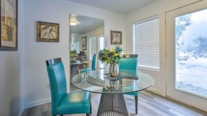 A dining area with a glass table and teal chairs, a vase with flowers, and framed artwork on the walls. - Cozy Darrington Cottage w/ Grill, Near Trails (Darrington)