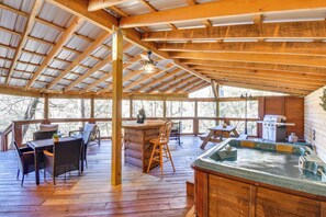 Eine Holzterrasse mit Whirlpool, Sitzgelegenheiten im Freien und Grillbereich.