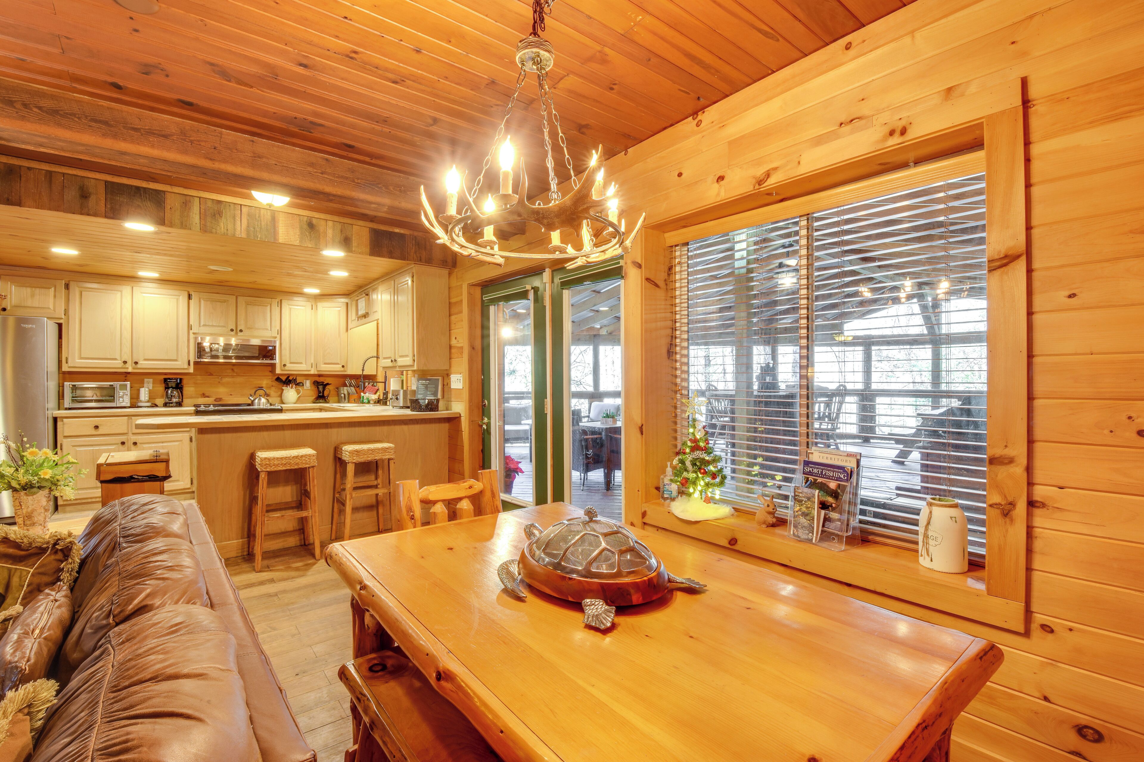 A wooden cabin interior with a dining table, a leather couch, and a turtle sculpture.