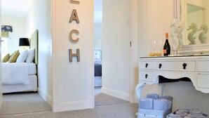 A bedroom with a bed, a dresser, a mirror, and a wall with the word 'BEACH' spelled out. - 3 bedroom accommodation in Beadnell (Beadnell)