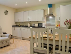 A modern kitchen with white cabinets, a stainless steel range hood, a microwave, and a dining table with chairs. - The perfect place to come and relax and unwind. (Aberfoyle)