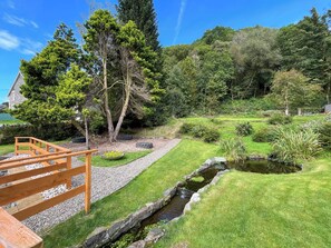 A garden with a wooden deck, a pond, and various plants.
