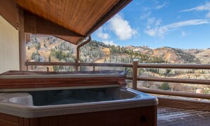 Ein Whirlpool auf einer Holzdielen-Terrasse mit Blick auf eine Berglandschaft.