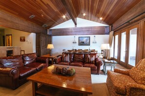 Ein geräumiges Wohnzimmer mit Holzboden, Ledersofas, einem Holztisch und einem Essbereich mit einer Chandelieber.