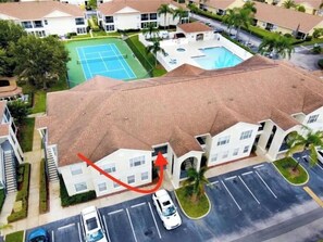 Un immeuble résidentiel doté d’un toit en tuiles, d’un court de tennis et d’une piscine.