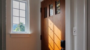 A hallway with a wooden door, a window, and a light switch.