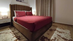 Een slaapkamer met een bed, nachtkastje en een schilderij aan de muur.