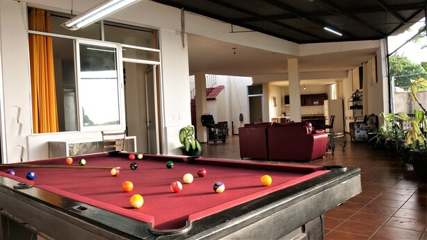 A pool table with balls, a red sofa, and a kitchen area in the background. - Casa Rinconsito Miramar (Santa Cruz)