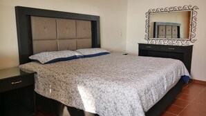 A bedroom with a bed, nightstands, a dresser, and a mirror. - Casa Rinconsito Miramar (Santa Cruz)