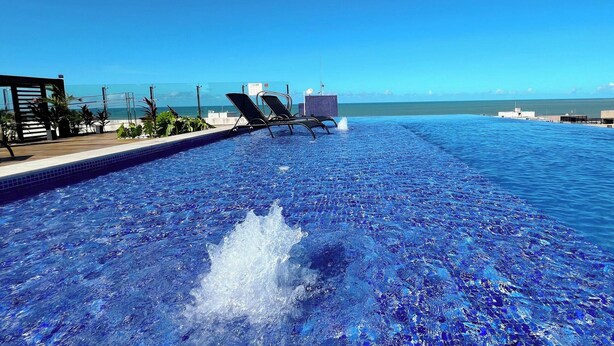 Une piscine avec des chaises longues et vue sur l’océan.