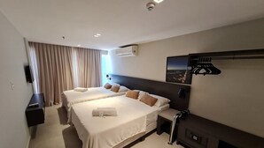 Une chambre d’hôtel avec deux lits, un téléviseur à écran plat, une cheminée et un tableau représentant un paysage urbain accroché au mur.