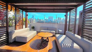 Un espace extérieur aménagé avec une table en bois, des canapés blancs et une vue sur la ville.
