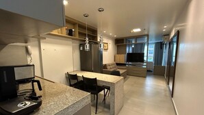 Une cuisine moderne avec un coin repas, un canapé, une télévision et un réfrigérateur.