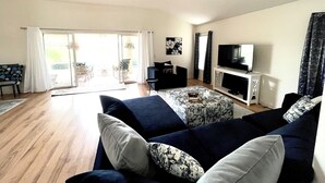 A living room with a sofa, a television, and a sliding glass door leading to an outdoor area. - Golf View in the Villages (The Villages)