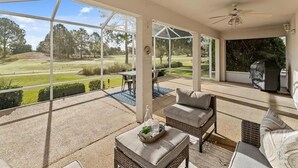 A covered patio with a view of a golf course, outdoor furniture, and a ceiling fan. - Golf View in the Villages (The Villages)