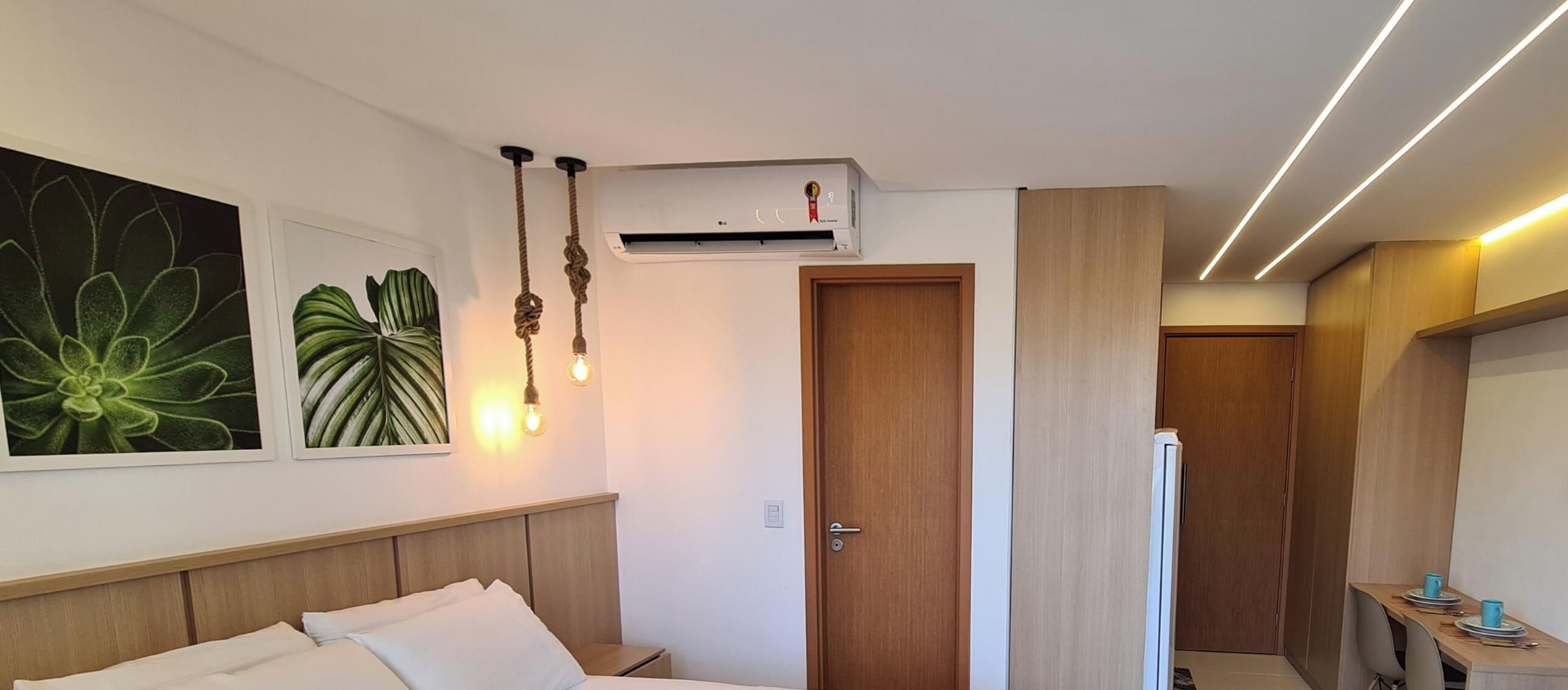 Et hotelværelse med en seng, et natbord og et skrivebord med stole. Der er en dør til et badeværelse og et tekøkken.