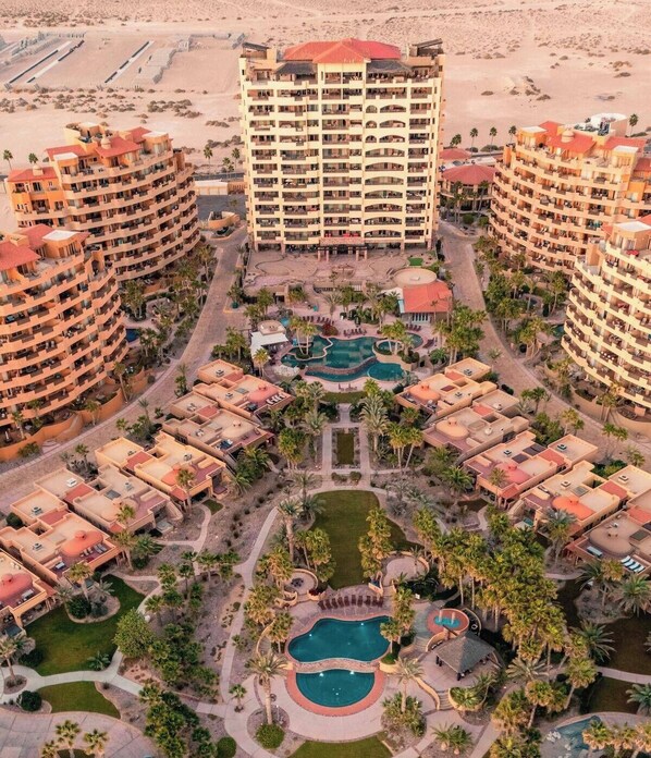 A resort with multiple buildings, a central pool area, and surrounding greenery.