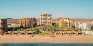 Ein Küstenort mit mehreren Hochhäusern, einem Sandstrand und Palmen.