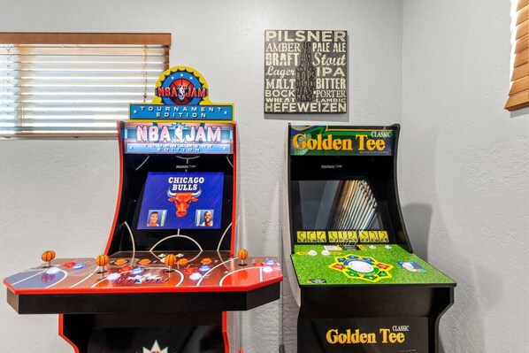 Deux bornes d’arcade : l’une est étiquetée « NBA JAM Tournament Edition » et l’autre « Golden Tee Classic ».