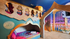 Una habitación con una cama, una pared con figuras recortadas y un mural.