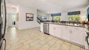 Una cocina amplia con una isla central, armarios blancos y vistas al exterior.