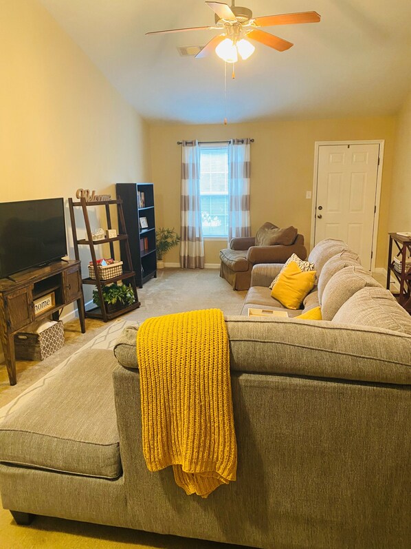 Relax in this inviting living space with a large sectional sofa, armchair, and smaller couch, perfect for unwinding.