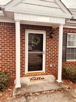 Welcome to a charming home with a brick facade, white door, and inviting porch.