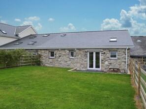 A stone building with a sloped roof, a front door, and a small porch.