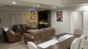 A living room with a brown leather sofa, a dining table with chairs, a fireplace, and a Christmas tree. - Casa Recuerdos (Del Rio)