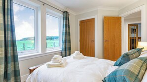 Una camera da letto con un letto, due porte in legno, una finestra con tende e vista su un paesaggio verde.