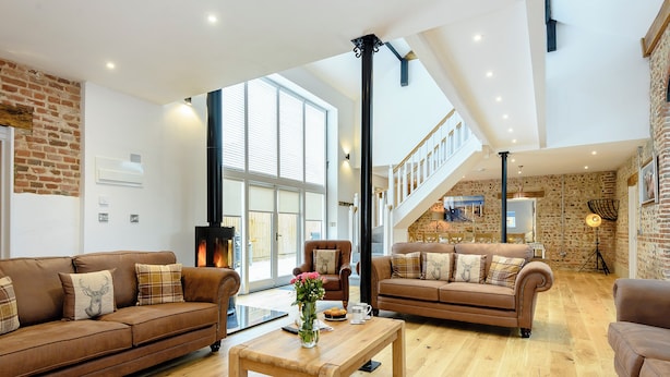 Un amplio espacio de sala con dos sofás de cuero marrón, una mesa de centro de madera y una chimenea.