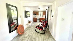 A spacious living area with a wooden floor, a rocking chair, a small table, and a kitchen in the background. - Studio in Little Havana - Free Gated Parking (Miami)
