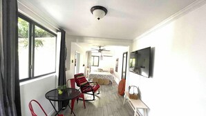 A room with a bed, a TV, a dining table with chairs, and a window with curtains. - Studio in Little Havana - Free Gated Parking (Miami)