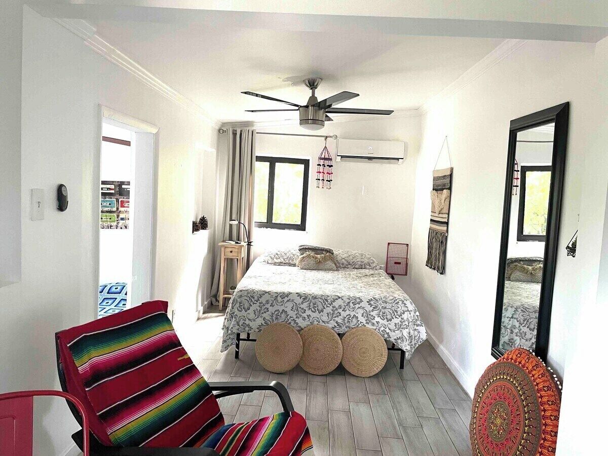 Ein Schlafzimmer mit Bett, Sessel, Deckenventilator und Fenster.