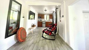 A hallway leading to a kitchen and dining area with a mirror, a patterned cushion, and a rocking chair. - Studio in Little Havana - Free Gated Parking (Miami)
