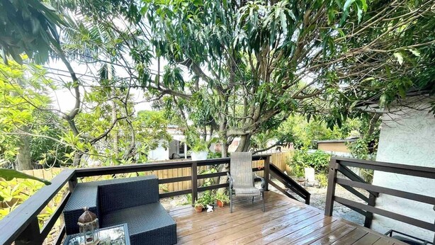 A wooden deck with outdoor furniture, a railing, and a tree providing shade. - Studio in Little Havana - Free Gated Parking (Miami)