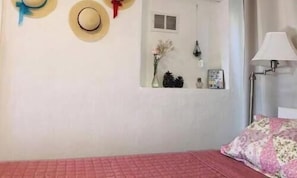 Une chambre à coucher avec un lit, une lampe et un miroir fixé au mur.