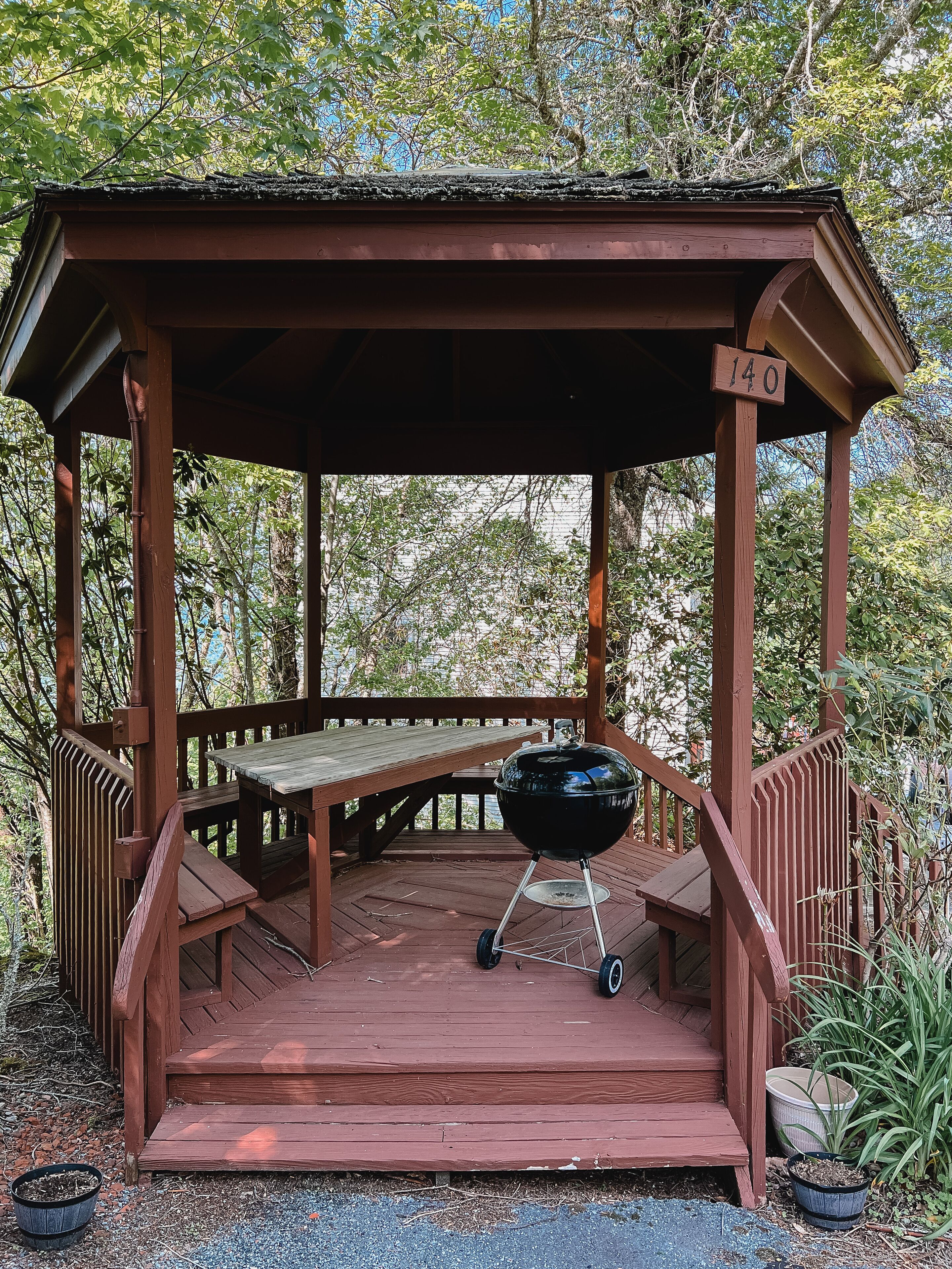 Ein Holz-Pavillon mit Grill, Treppe und Hinweisschild.
