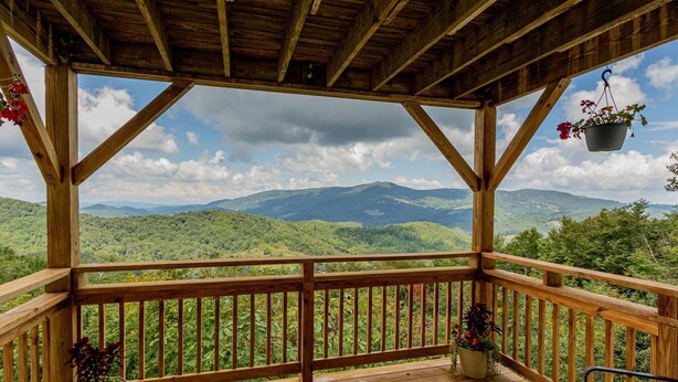 Una terraza de madera con vistas a colinas y montañas verdes.