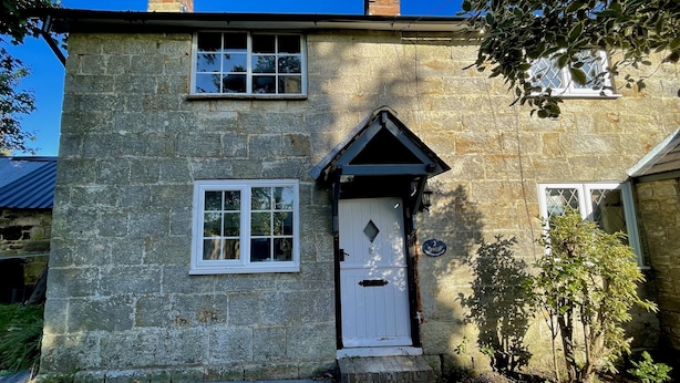 A stone house with a white door, a small window, and a chimney. - Cosy Victorian Cottage in Crowborough with Log Burner and parking (Crowborough)