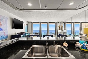 Une cuisine moderne dotée d’un grand îlot central, de deux éviers et offrant une vue sur l’océan.