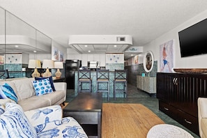 A modern living room with a sofa, coffee table, and a TV mounted on the wall. - Turtle Nest- Edgewater T3-Beachfront-1 BD/1BTH-Sleeps 4-Mesmerizing Views! (Panama City Beach)