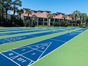 A shuffleboard court with numbered scoring areas and a building with red-tiled roofs in the background. - Paradise Palms Edgewater T3-Beachfront-1 BD/1BTH-Sleeps 4-Mesmerizing Views! (Panama City Beach)